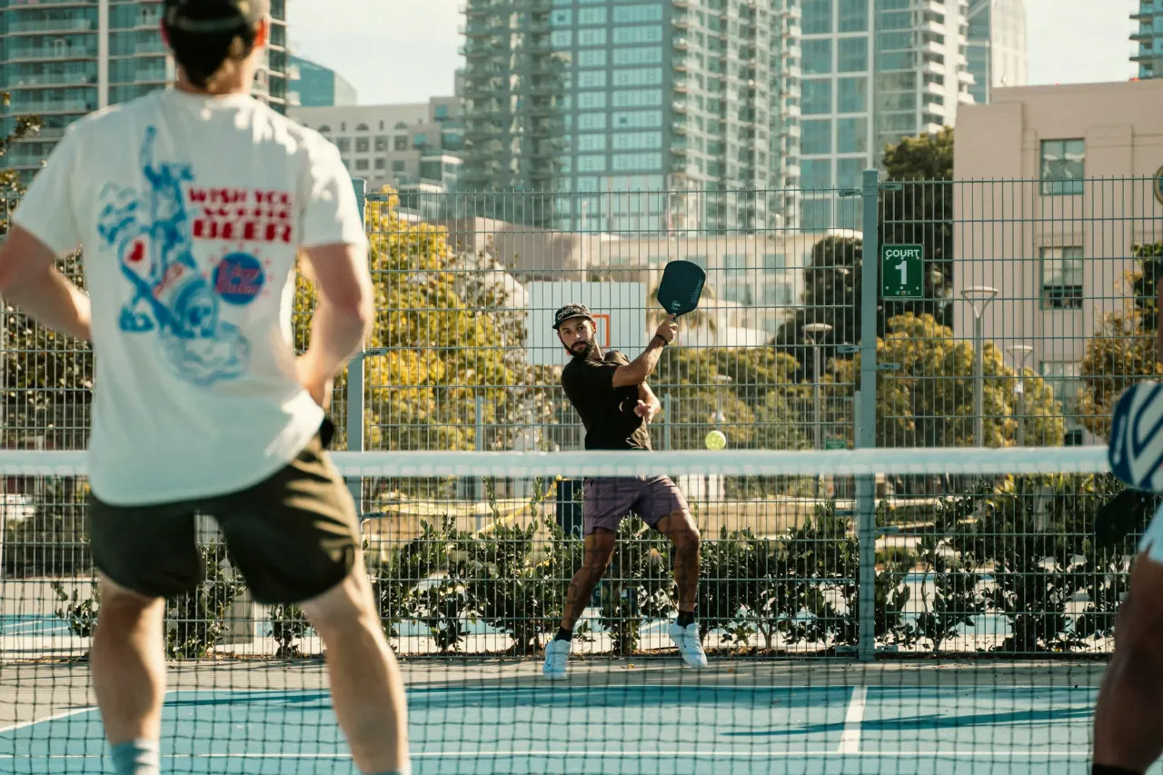 Players rallying at the net on an outdoor pickleball court